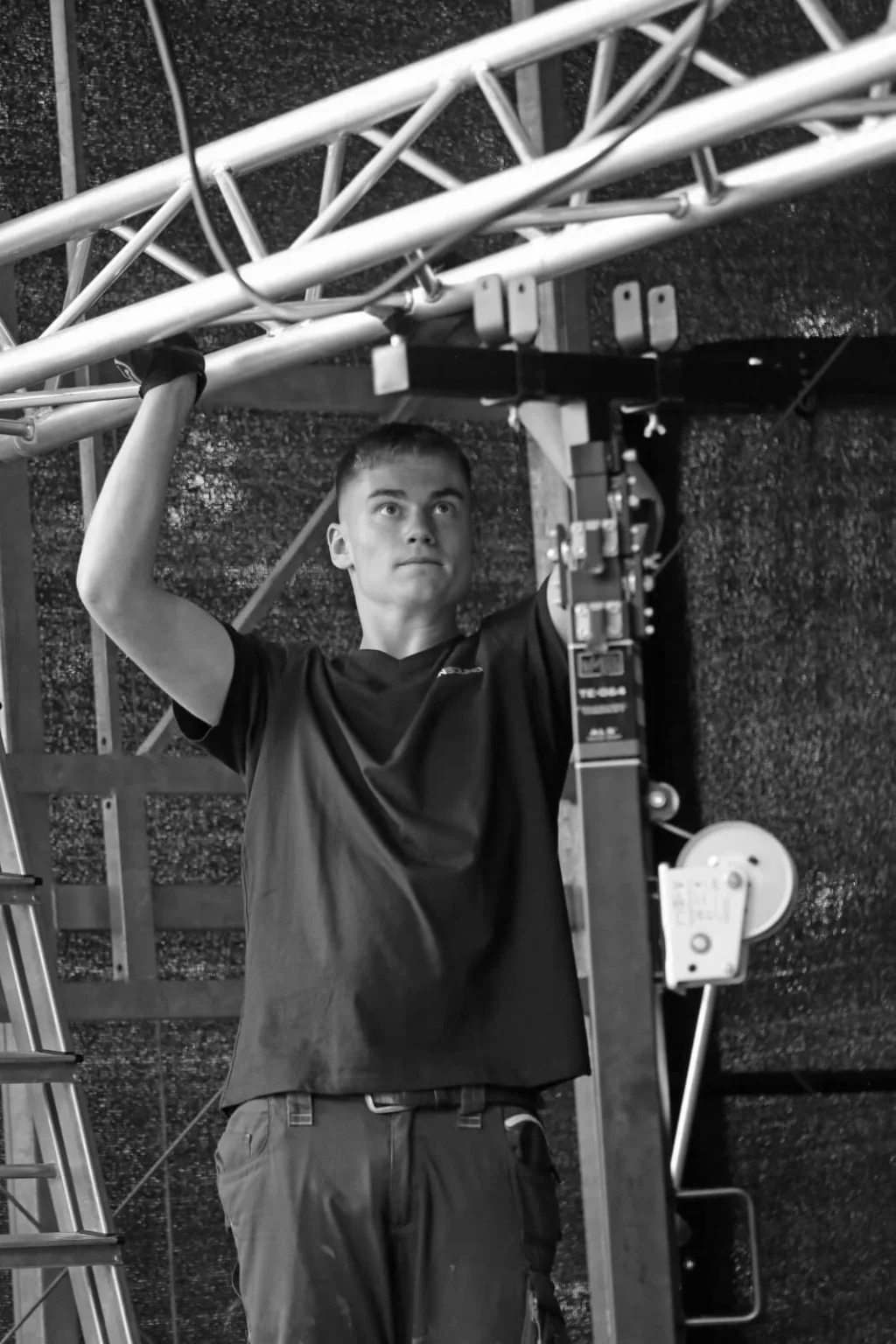 Ein Techniker von ActionSound befestigt eine Traverse während des Bühnenaufbaus.